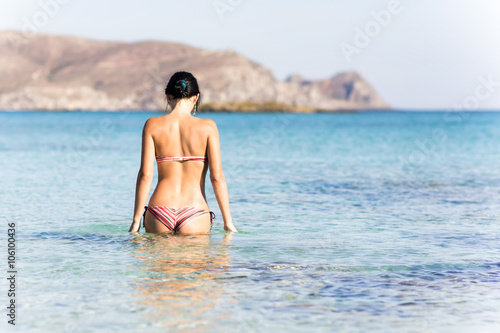 Стройная девушка входит в чистую воду моря