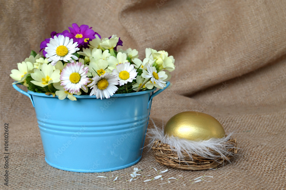 Golden Easter egg in the nest and spring flowers Golden Easter egg in the nest and spring flowers