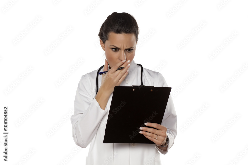 amazed woman doctor in uniform reading her clipboard amazed woman doctor in uniform reading her clipboard