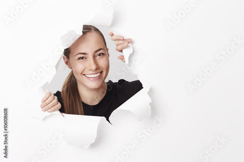 Portrait of smiling young woman emerging from paper