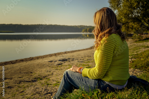 Kobieta siedząca nad jeziorem