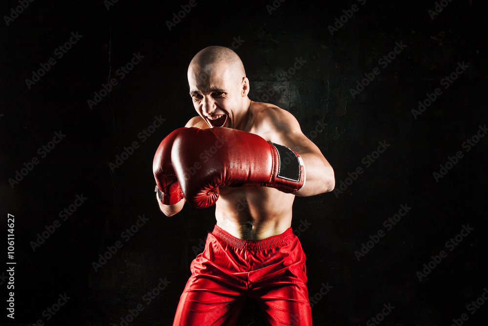 The young man kickboxing on black