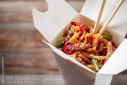 Bilde på lerret Noodles with pork and vegetables in take-out box on wooden table