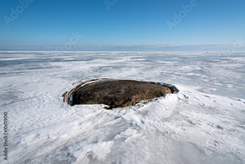 black stone in a frozen lake © comradelukich