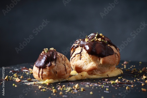 Tableau sur toile Profiteroles with cream,chiocolate and pistachios