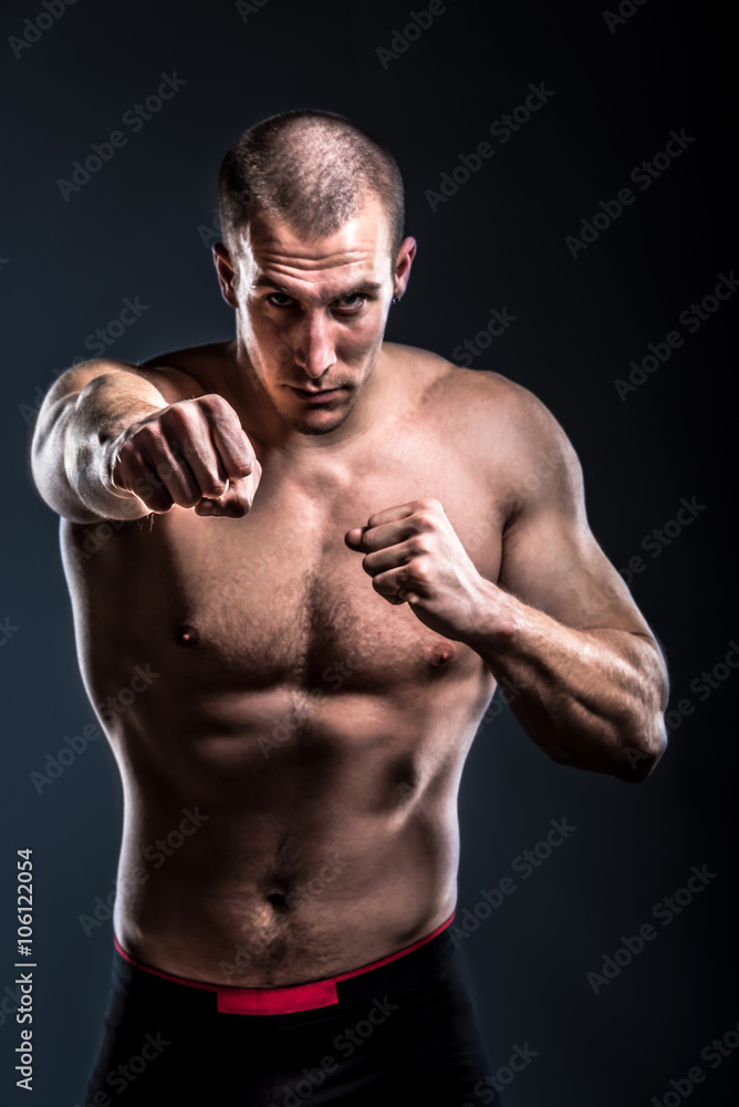 fighter posing shirtless and with bare knuckles on dark background - punch