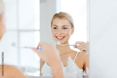 Foto woman with toothbrush cleaning teeth at bathroom