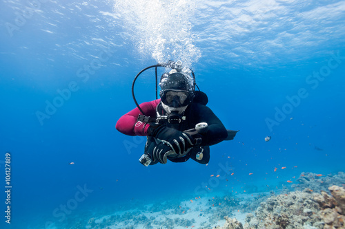 Scuba diver floating over coral reef in the Red Sea and looking to the camera.