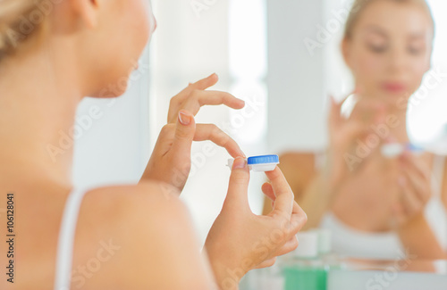 young woman applying contact lenses at bathroom