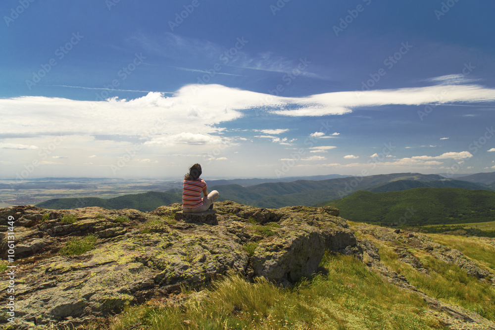 Young woman relaxing on the rocks in high mountain