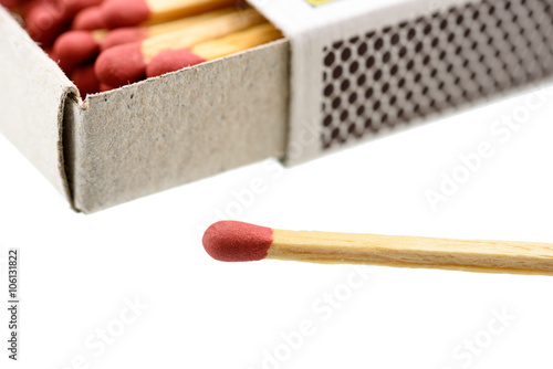 Matchbox, a small paperboard box enclosing a quantity of matches in the interior tray and having a coarse striking surface on the exterior. With a matchstick outside box isolated on white background. photo