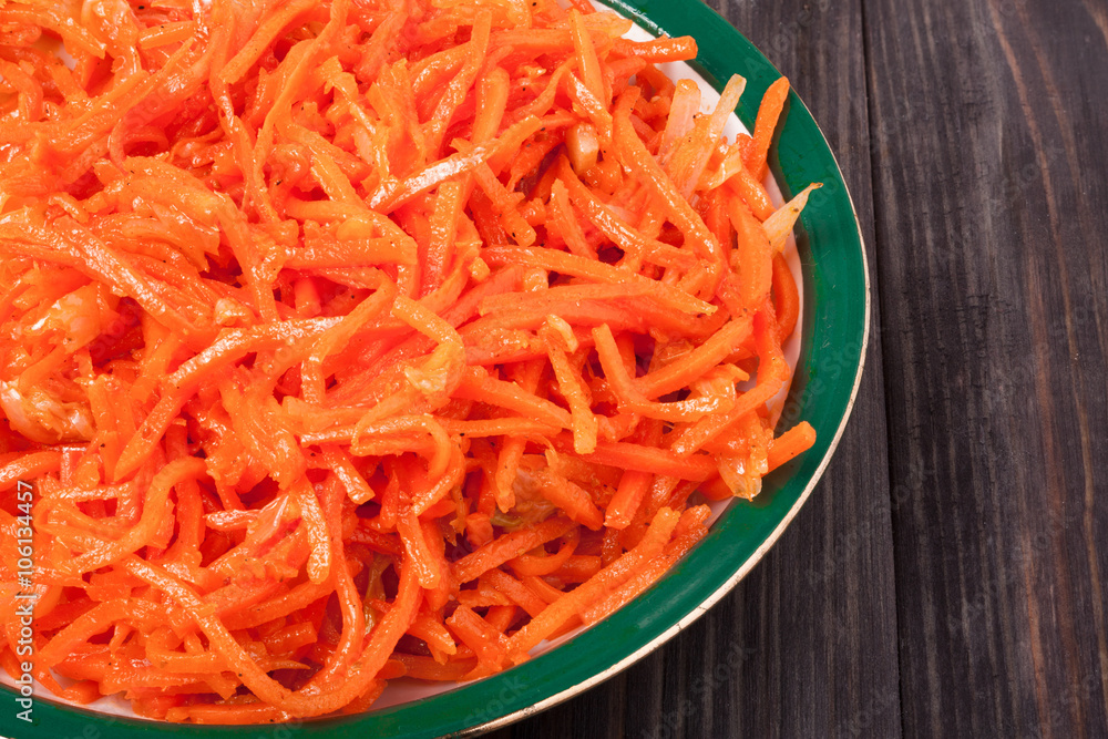 Hot carrot salad in plate on wooden background Hot carrot salad in plate on wooden background