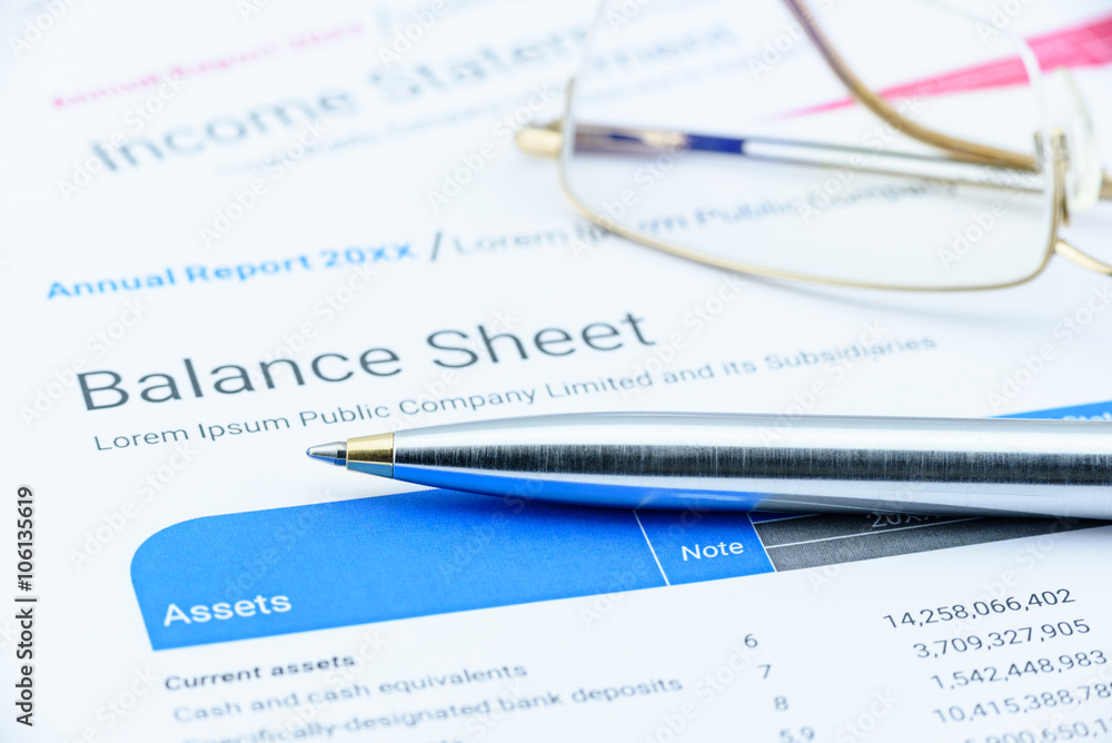 Blue ballpoint pen on a corporate balance sheet with eye glasses waiting for an auditor to audit before passing to executive committee in the boardroom. Financial and investment analysis concept. Blue ballpoint pen on a corporate balance sheet with eye glasses waiting for an auditor to audit before passing to executive committee in the boardroom. Financial and investment analysis concept.