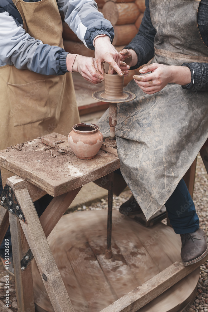 The hands of potter help make  pitcher on  pottery wheel