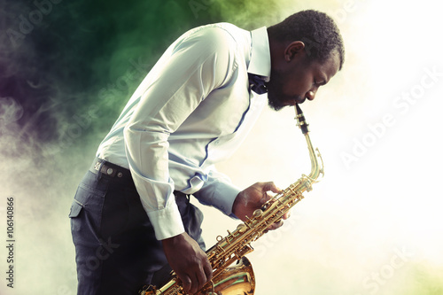Photography African American jazz musician playing the saxophone against smoky background