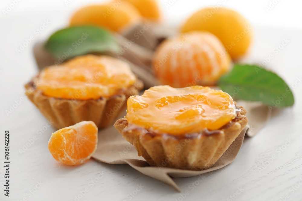 Sweet cakes with tangerines on table, close up Sweet cakes with tangerines on table, close up