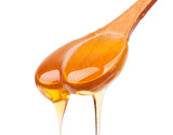 Honey dripping from a wooden spoon isolated