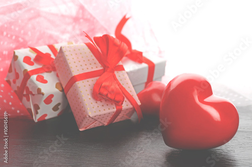 Gift boxes and decorative hearts on wooden table, on light background