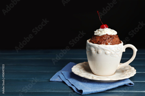 Chocolate mug cake with cream and cherry on a table in front of dark background