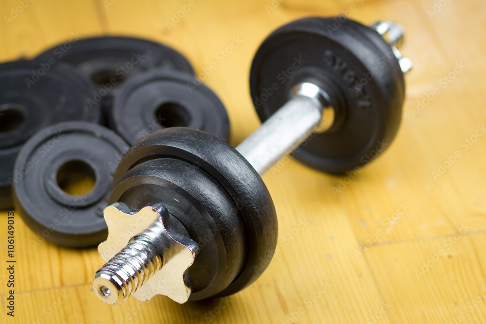 Big black dumbells on wood floor in the huge gym / fitness; spor Big black dumbells on wood floor in the huge gym / fitness; spor