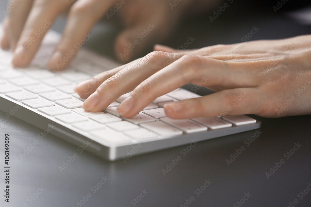 Female hands using keyboard on dark wooden table, close up Female hands using keyboard on dark wooden table, close up