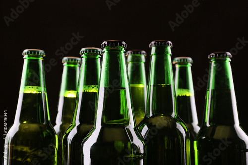 Green glass bottles of beer on dark background, close up