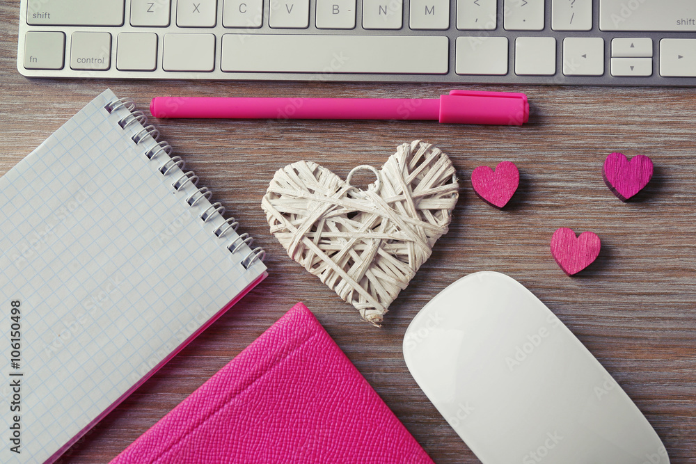 Fototapeta premium Computer peripherals with hearts, pen and notebooks on wooden table