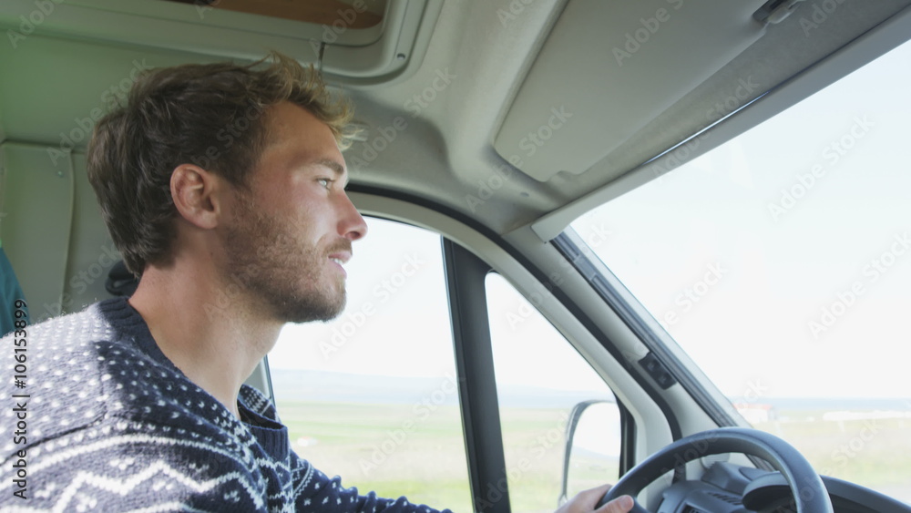 Young man driving mobile home car. Side view portrait of smiling male on roadtrip. Handsome man is concentrating while driving automobile motorhome. Young man driving mobile home car. Side view portrait of smiling male on roadtrip. Handsome man is concentrating while driving automobile motorhome.