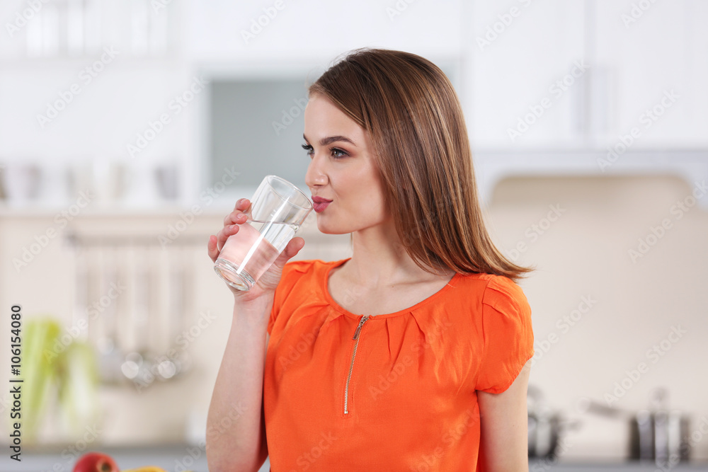 Young woman drinking water from glass in the kitchen Young woman drinking water from glass in the kitchen