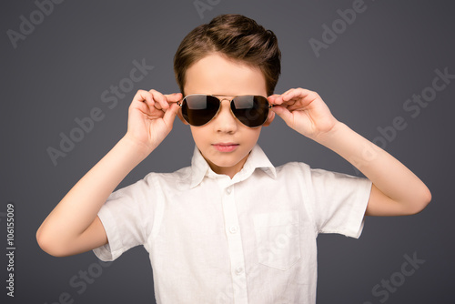 Stylish handsome little schoolboy touching his glasses
