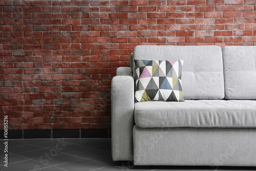 Grey sofa against brick wall in the room © Africa Studio