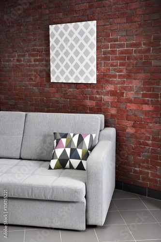 Grey sofa against brick wal...
