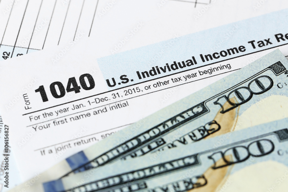 Obraz premium 1040 Individual Income Tax Return Form with one hundred dollar bills, close up