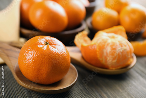 Fresh delicious peeled and unpeeled tangerines on the wooden spoons, close up