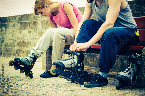 People friends putting on roller skates outdoor.