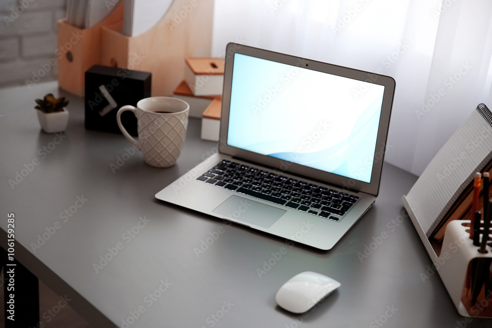 Workplace with laptop, table, mouse and cup beside the window Workplace with laptop, table, mouse and cup beside the window