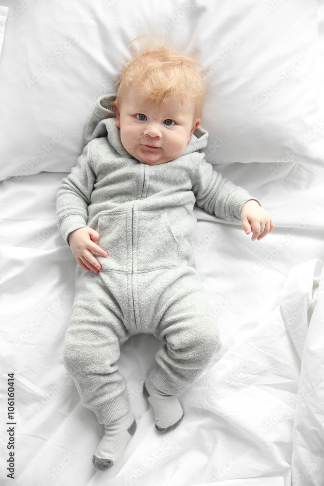Little baby boy in grey pajamas lying on the bed Little baby boy in grey pajamas lying on the bed