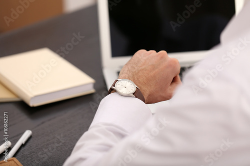 Businessman checking the time on his wrist watch, close up