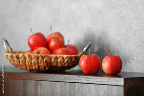 Wicker tray with ripe apples on wooden table