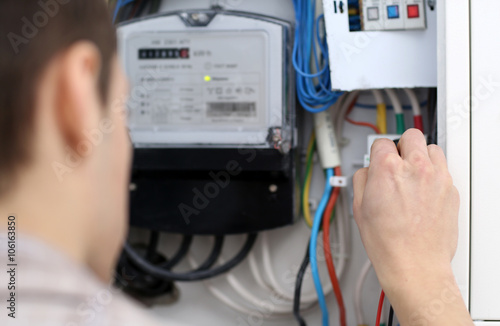 Young electrician checking voltage in fuse board