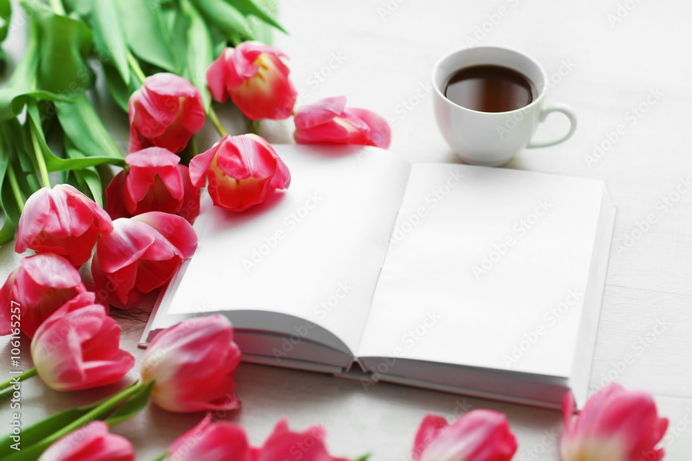 Pink fresh tulips and notebook on the white table, close up Pink fresh tulips and notebook on the white table, close up