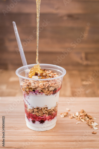 yogurt with granola,honey, almond and fresh berries on the bright wooden board
