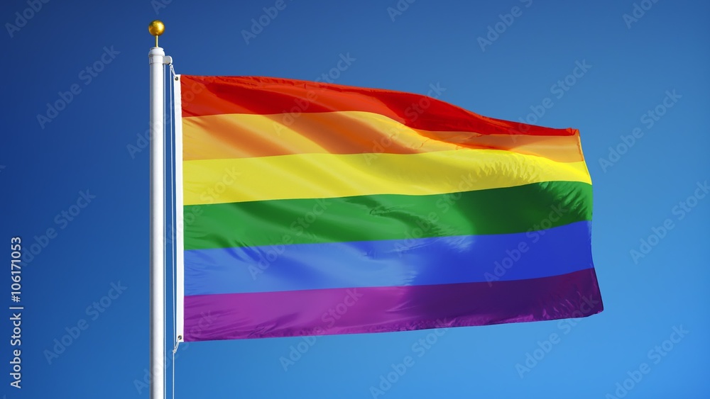 The gay pride rainbow flag waving in slow motion against clean blue sky ...