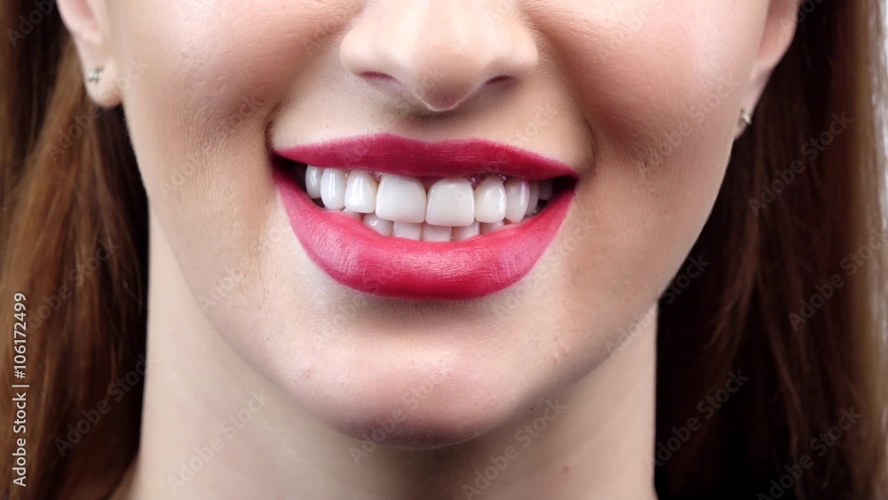Beautiful smiling young woman with perfect skin, red lipstick and teeth. Close up. Slow motion
