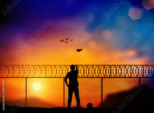 Silhouette of a prisoner behind a barbed wire fence, throw paper airplanes to fight outside the barbed wire fence over blurred nature. Concept Freedom, independent business, independent thinking.