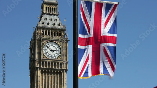 Big Ben clock face, on the Elizabeth Tower, with a Union Jack flag flying above the Houses of Parliament in London England