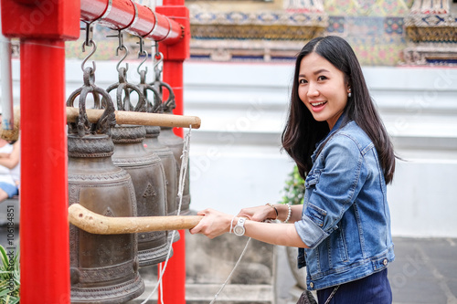 Woman ringing a bell in a Buddhist temple in Thailand photo