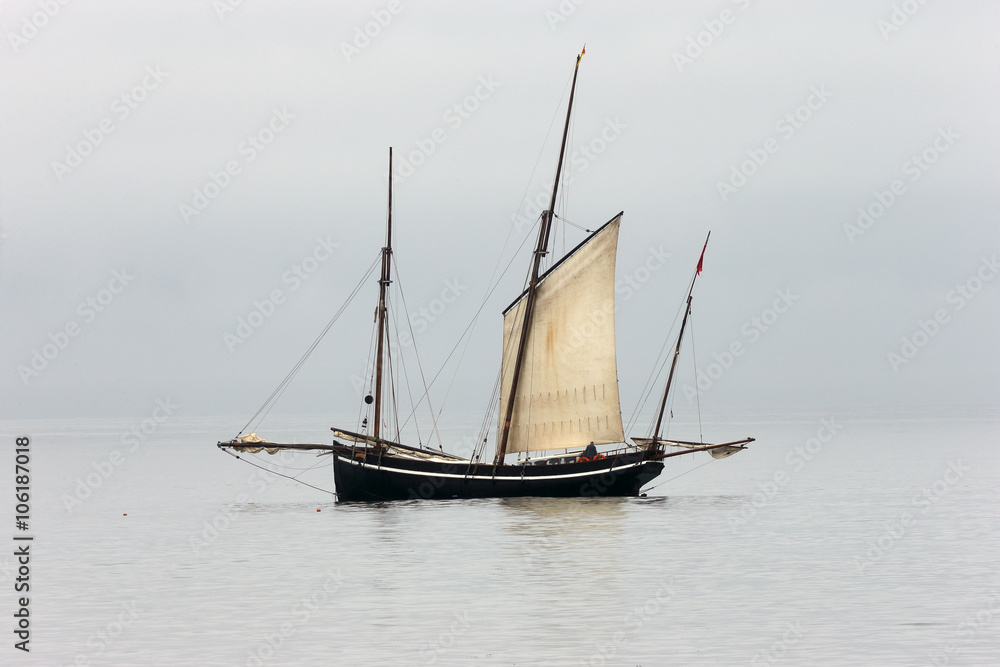 Ancient fishing boat, a Cornish lugger, becalmed off Newlyn, Cornwall, England, UK.