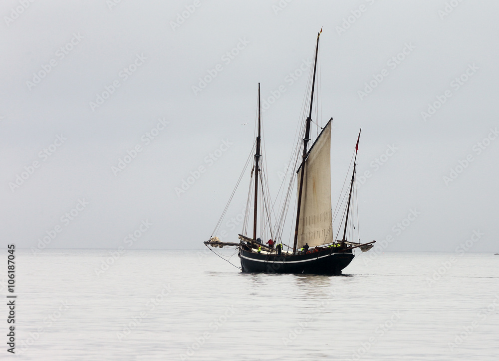 Ancient fishing boat, a Cornish lugger, becalmed off Newlyn, Cornwall, England, UK. Ancient fishing boat, a Cornish lugger, becalmed off Newlyn, Cornwall, England, UK.