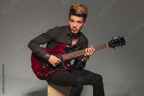 seated young man playing an electric guitar